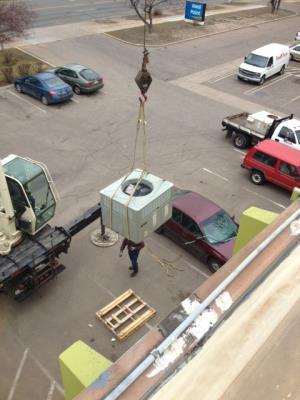 Crane is lifting the new rooftop unit onto roof.